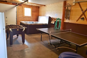 A room with a foosball table, a hot tub, and a ping pong table.