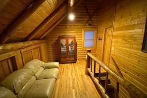 A log cabin interior with a loft bedroom, a wooden staircase, and a window with blinds. - Oct Special -Yellowstone Escape -Game Rm -Hot Tub (Island Park)