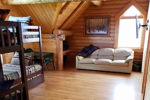Een gezellig vakantiehuisje met een stapelbed, een bank en een schilderij aan de muur.