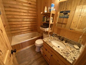 Bathroom features a bathtub, standard toilet, granite countertop, and a shelf for toiletries.