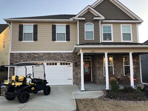 Stunning two-story residence with a covered entryway and porch, featuring a stone accent wall and a garage with a white door.