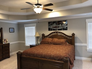 Cozy retreat with a traditional bed, ceiling fan, and window with blinds.