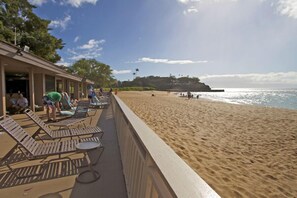 Ein Hotel am Strand mit Liegestühlen und Blick auf den Ozean.