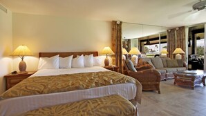 Una habitación de hotel con una cama grande, dos sillones, un sofá y una mesita.