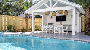 A poolside area with a covered patio, outdoor kitchen, and seating. - Indigo Cottage: Stylish Island Retreat | Walkable to Everything | Pool + Spa | Dogs Welcome (Saint Simons Island)