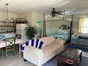 A compact living space with a kitchenette, a dining area, a sofa, a bed with patterned bedding, and a ceiling fan. - Private Cozy Studio in Navarre FL (Navarre)