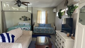 A compact room with a bed, a sofa, a TV, and a small table.