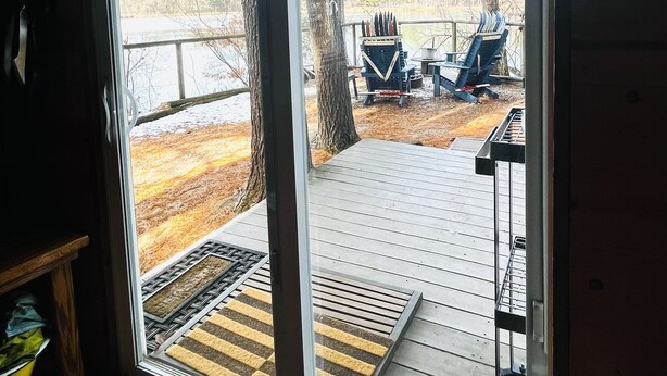 A room with a sliding glass door leading to an outdoor deck with chairs and a picnic table.
