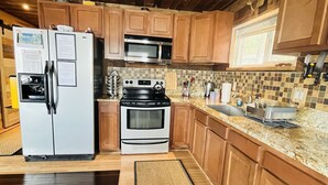 A modern kitchen with wooden cabinets, stainless steel appliances, and a tiled backsplash.
