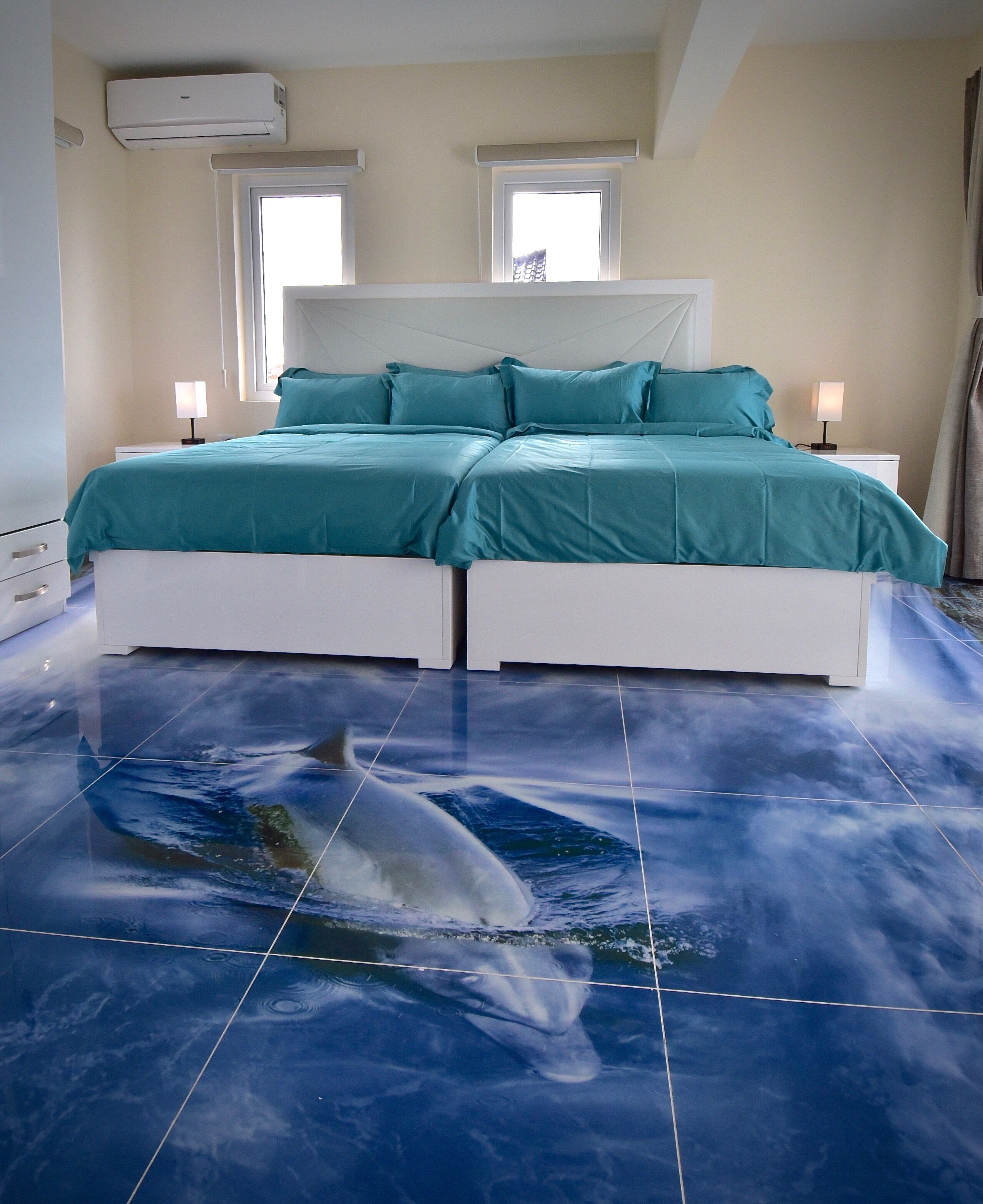 Une chambre à coucher comprenant un lit, deux tables de chevet et un climatiseur fixé au plafond.
