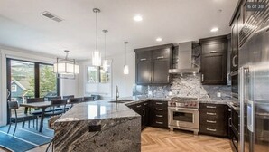 A modern kitchen with dark cabinets, a marble countertop, and stainless steel appliances. - 3 min walk to Ski/bike main PCMR lift or Main Street!August and September deals! (Park City)