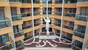 A multi-story hotel with balconies, a central courtyard with a statue, and a patterned floor design. - TAC Premier Hotel - SPA (ALANYA)
