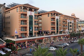 A multi-story hotel with a central atrium, balconies, and a ground-level commercial area with shops and a food court. - TAC Premier Hotel - SPA (ALANYA)