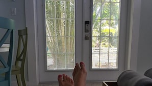 A room with a door leading to a balcony, a chair, and a wooden box with towels.