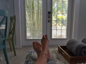 A room with a door leading to a balcony, a chair, and a wooden box with towels.