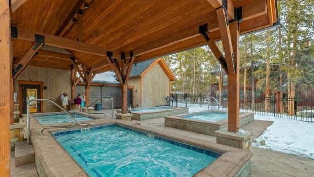 Eine Holzterrasse mit Whirlpool und Poolbereich.
