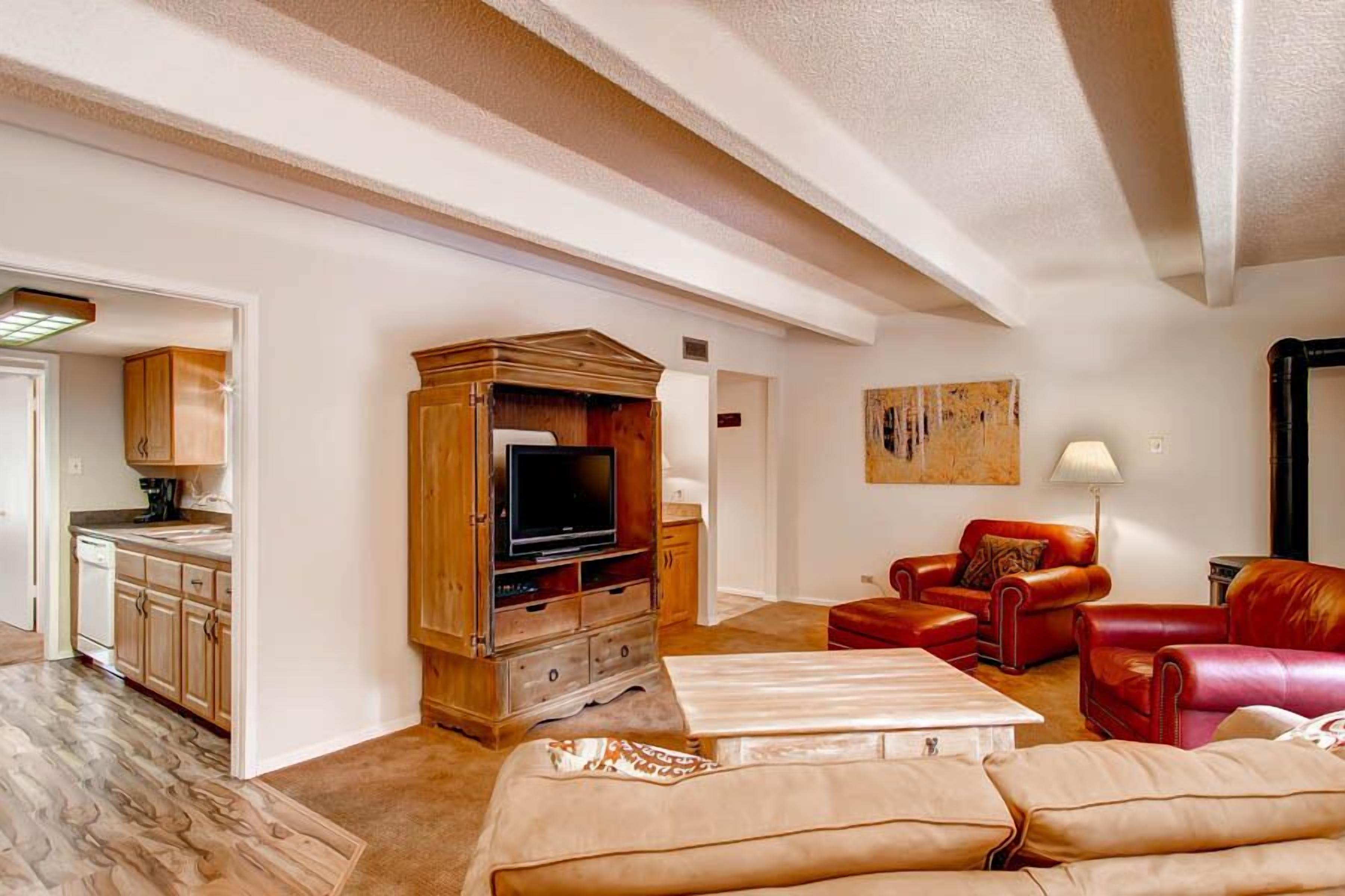 Una sala de estar con un mueble de entretenimiento de madera, sofás de cuero rojo y una mesa de centro blanca.