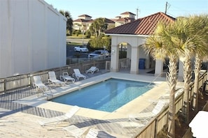 Relax by the clear pool surrounded by lounge chairs and palm trees.