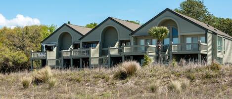 A beachfront property with multiple rooms featuring balconies and a pool area.