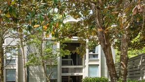 A two-story building with a balcony and a small porch.