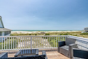 Een terras met rieten meubilair met uitzicht op een strand.