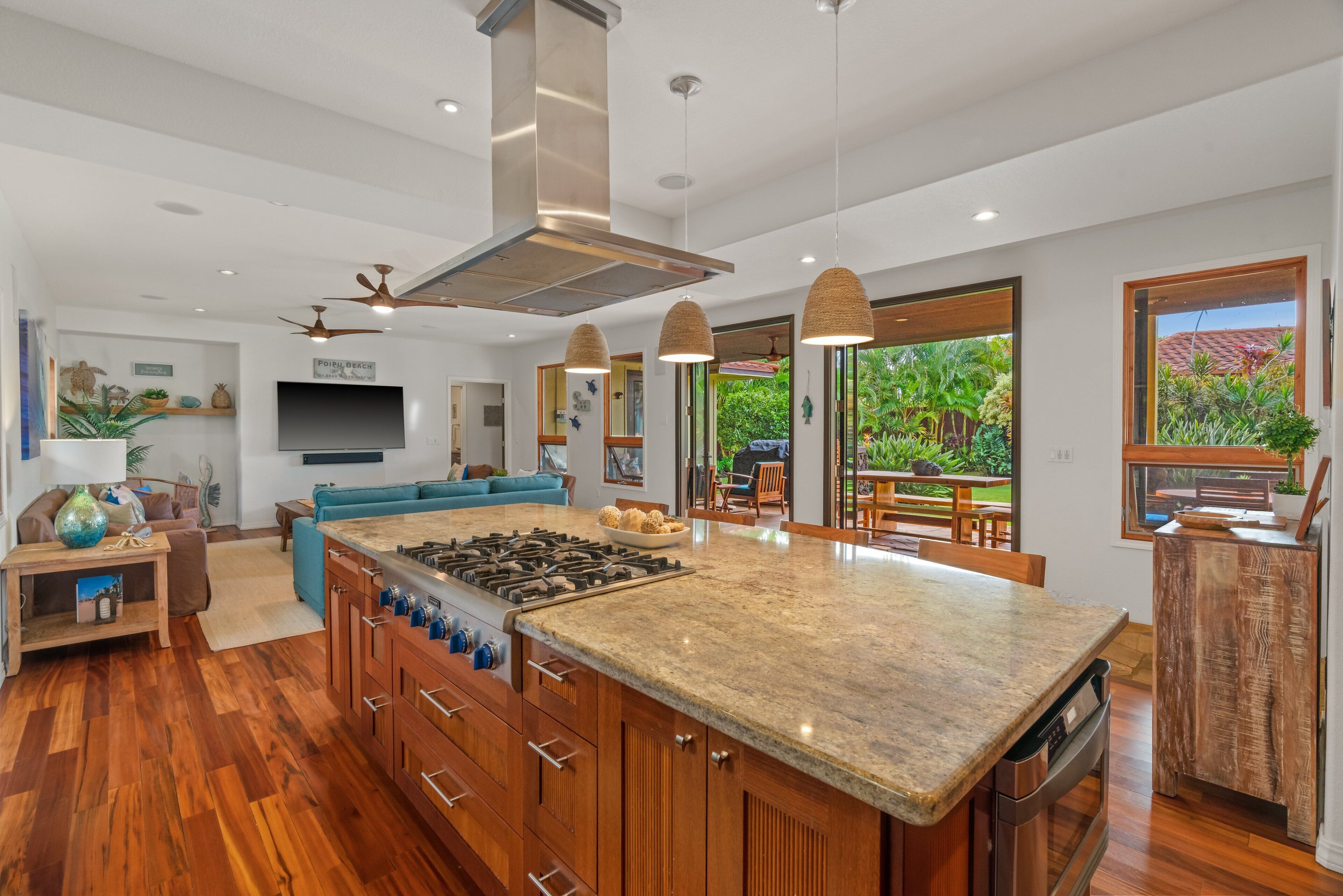 A spacious kitchen with a large island, wooden cabinets, and a central range hood.