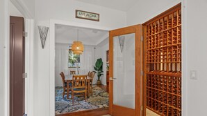 Un passage mène à un coin repas comprenant une table et des chaises, un luminaire suspendu et un meuble à vin.