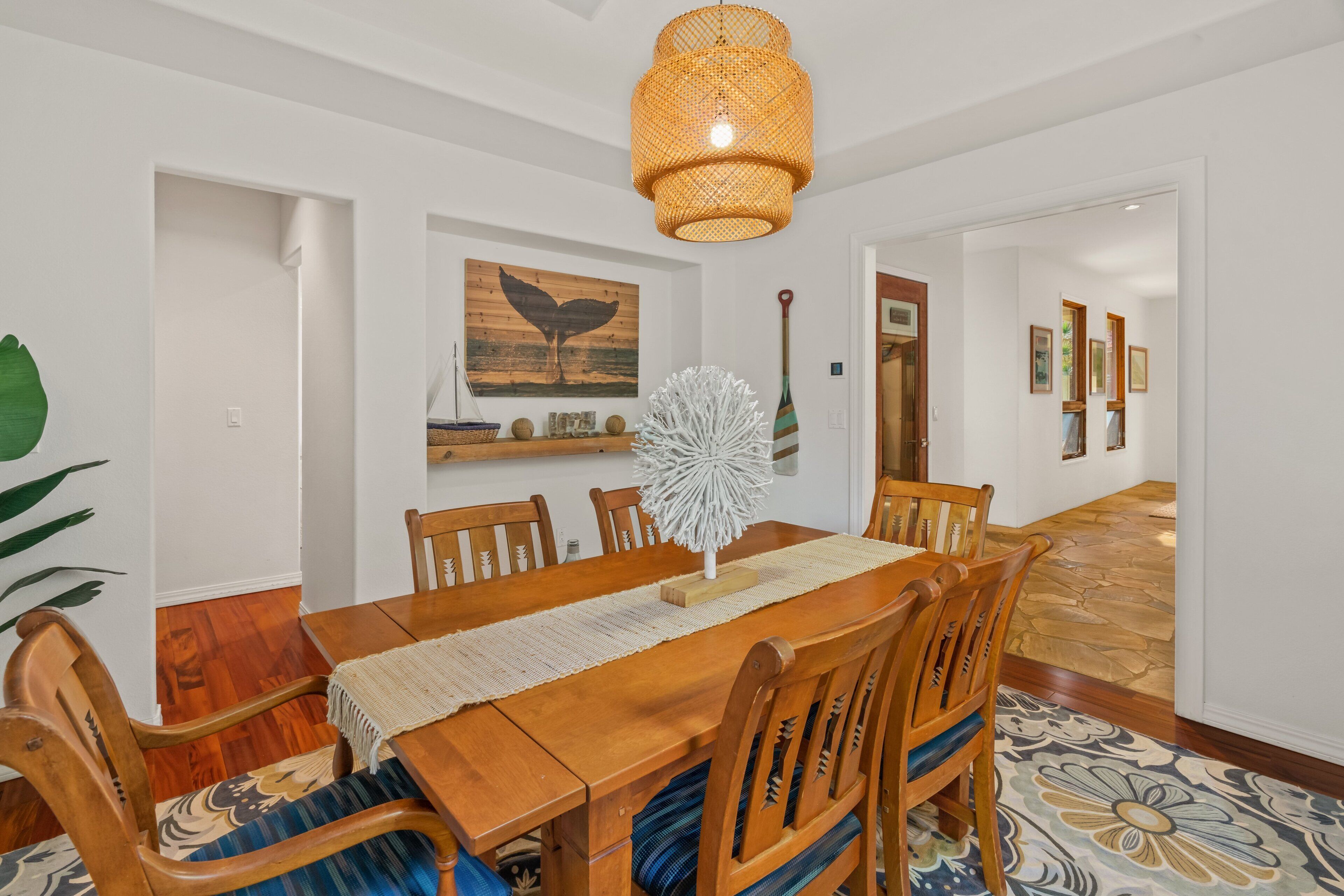 A dining area with a wooden table, chairs, a woven light fixture, and a decorative white sculpture.