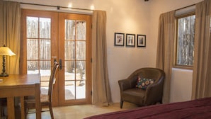 Une pièce avec une porte en bois, une chaise, un lit et une fenêtre.