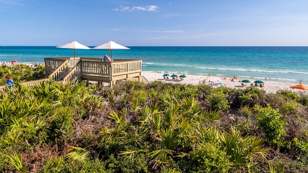 A beach with a wooden structure, beach umbrellas, and people relaxing. - Find The Best Seat at The Front Row / Quiet Area on St. Augustine Green in Rosemary / 4 Bikes (Panama City Beach)