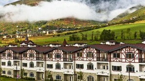 A traditional chalet-style hotel with multiple balconies and a mountainous backdrop.