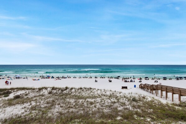 A beach with a wooden boardwalk and white sand.
