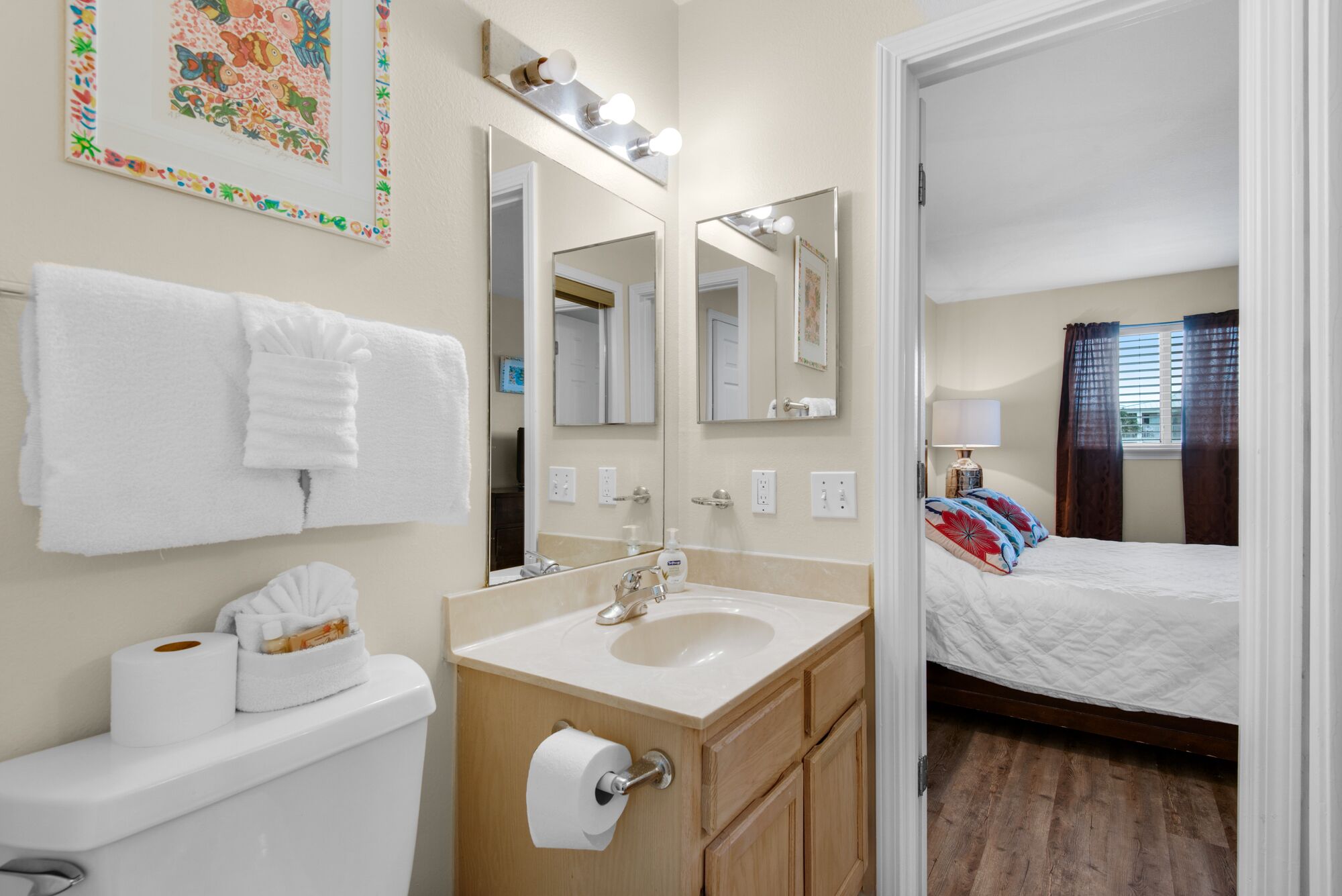 Un baño de hotel con lavamanos, espejo e inodoro.