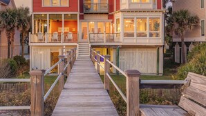 Una casa a più piani con una veranda in legno che conduce all'ingresso.