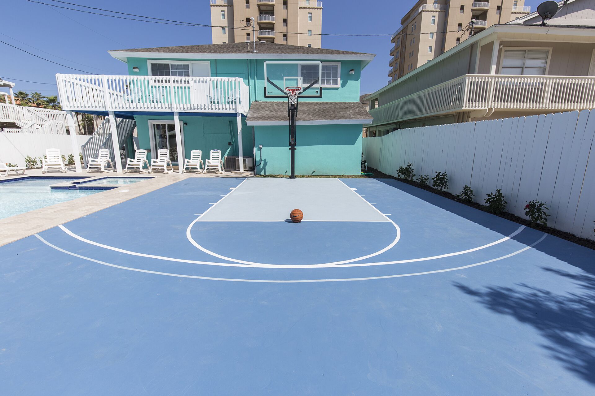 En basketplan med en pool och solstolar.