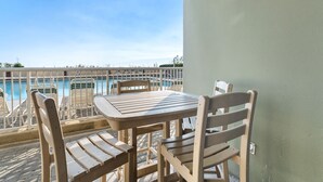 A balcony with a table and chairs overlooking a pool. - Waters Edge 109 ~ Ground Floor and Beach Front ~ Steps to Pool and Sand! (Fort Walton Beach)