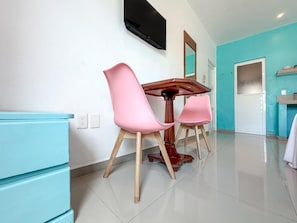Una cucina moderna con mobili color petrolio, un tavolo da pranzo in legno e sedie rosa.