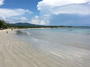 A beach with clear water, a sandy shore, and a mountain in the background. -  vista al mar/partial ocean view suite (Punta de Mita)