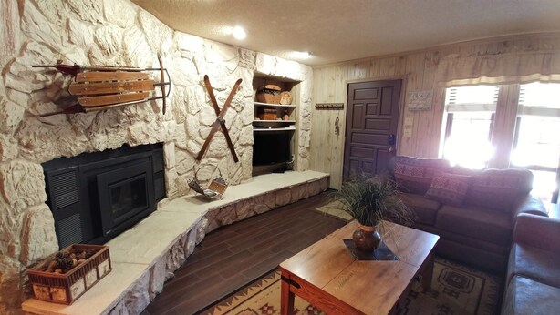 Una sala de estar con chimenea de piedra, estanterías de madera, un sofá y una mesa de centro.