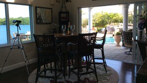 Comedor con vistas a un lago, un trípode y mobiliario exterior junto a una piscina.