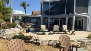 Una casa moderna con piscina, mobiliario exterior y un patio cubierto.