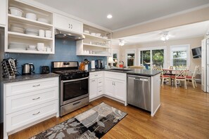A modern kitchen with white cabinetry, stainless steel appliances, and a blue backsplash.
