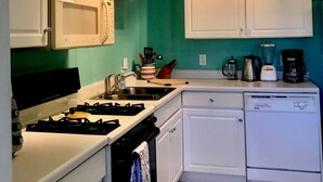 A compact kitchen with white cabinets, a stove, a dishwasher, and a coffee maker. - Comfort by the river & short walk to downtown. (Salida)