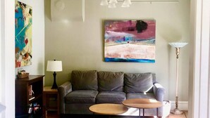 A living room with a sofa, two coffee tables, a lamp, and a painting on the wall. - Comfort by the river & short walk to downtown. (Salida)