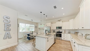 A spacious kitchen with white cabinetry, a central island, and pendant lighting.