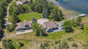 An aerial view of a residential area with two houses, a dock, and a boat. - Beside Quiet Waters | Waterfront | Lake Bellaire (Bellaire)