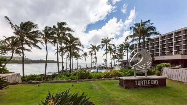 A resort with a view of the ocean, palm trees, and a sign reading "Turtle Bay." - Keone Nani Condo - New AC, Golf, Swim, Food Trucks (Kahuku)