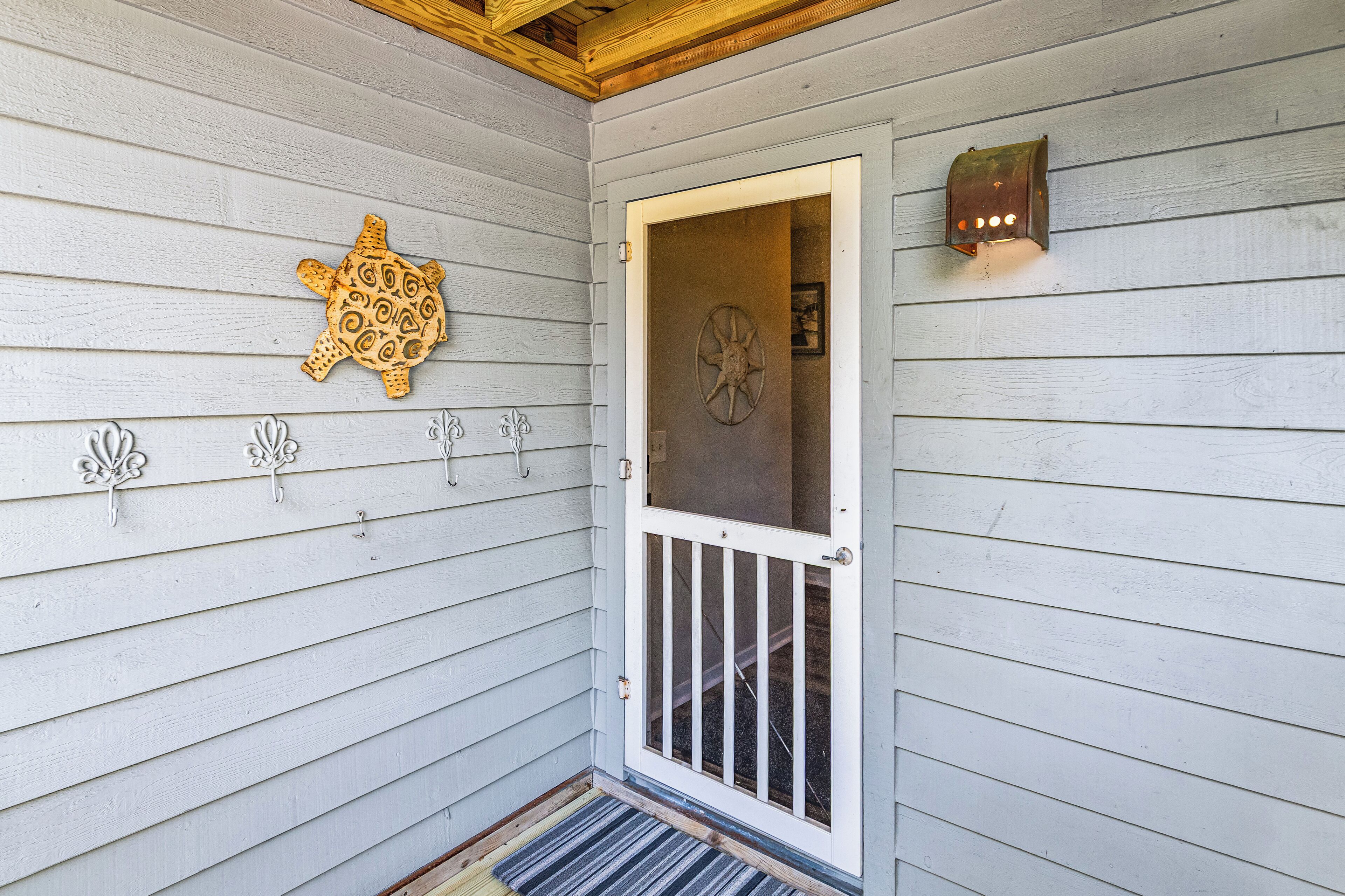 A wooden door with a glass panel, a decorative turtle plaque, and a wall-mounted light fixture.
