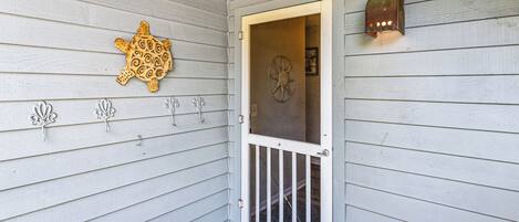 A wooden door with a glass panel, a decorative turtle plaque, and a wall-mounted light fixture.