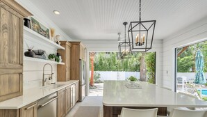 A modern kitchen with wooden cabinets, a white countertop, and a large island with seating. - Magnificent East Beach Home! Heated Pool, 5BR/5.5BA Sleeps 16 (St. Simons Island)